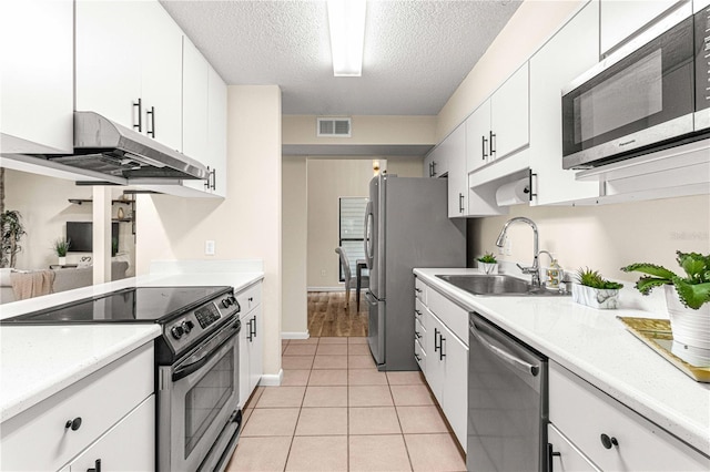 kitchen featuring sink, white cabinetry, stainless steel appliances, a textured ceiling, and light tile patterned floors