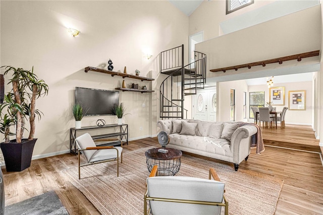 living room with high vaulted ceiling, an inviting chandelier, and light hardwood / wood-style flooring