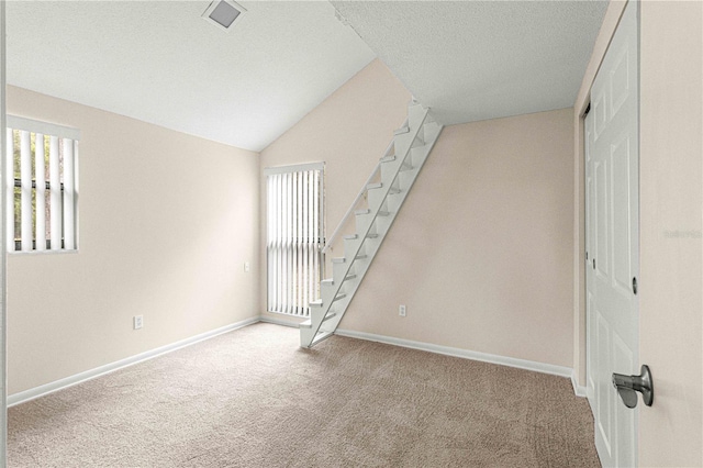 carpeted spare room featuring vaulted ceiling