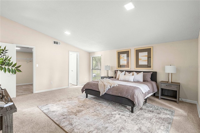 carpeted bedroom featuring lofted ceiling, a walk in closet, and a closet