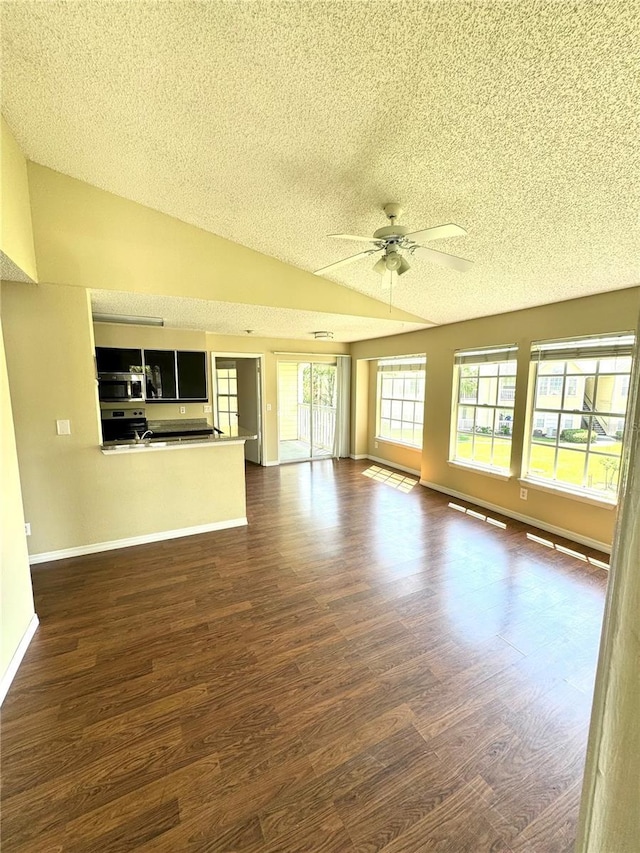 unfurnished living room with ceiling fan, vaulted ceiling, dark wood finished floors, and a textured ceiling