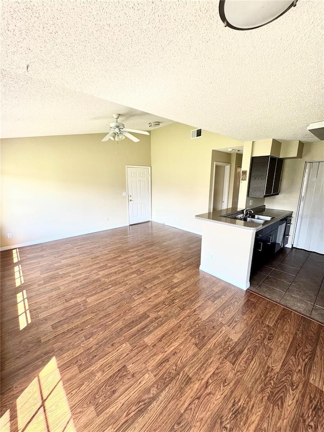 kitchen with a ceiling fan, a textured ceiling, dark countertops, dark wood-style floors, and open floor plan