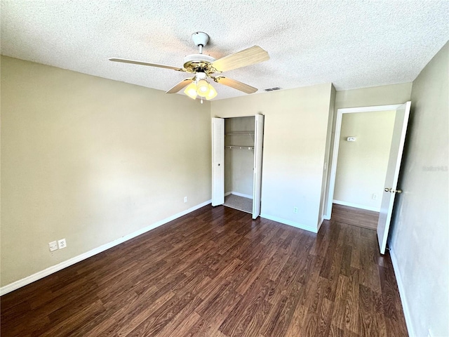 unfurnished bedroom featuring ceiling fan, a textured ceiling, baseboards, a closet, and dark wood-style floors