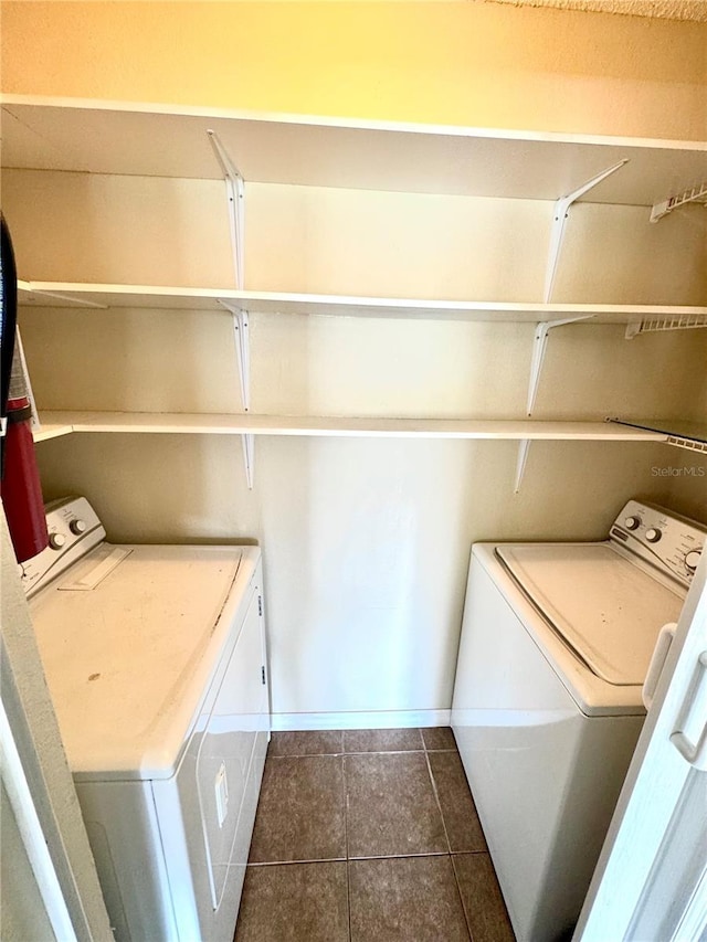 laundry area with dark tile patterned flooring, baseboards, laundry area, and washer and dryer