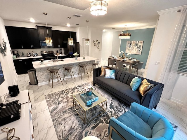 living room featuring a textured ceiling, crown molding, sink, and an inviting chandelier