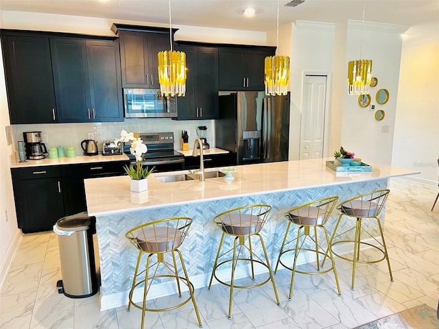 kitchen featuring appliances with stainless steel finishes, a kitchen breakfast bar, a kitchen island with sink, sink, and pendant lighting