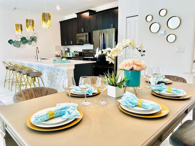 kitchen with pendant lighting, a breakfast bar, sink, an island with sink, and appliances with stainless steel finishes