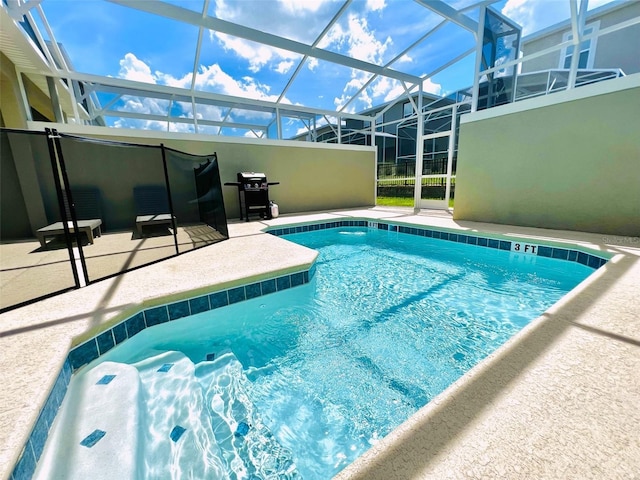 view of pool with glass enclosure, grilling area, and a patio area