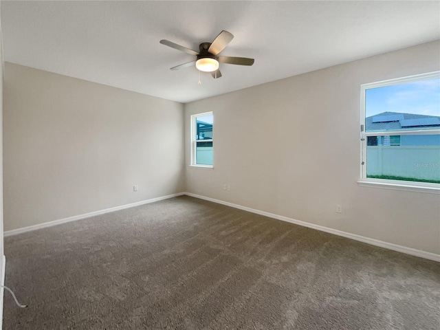 spare room featuring ceiling fan and dark colored carpet