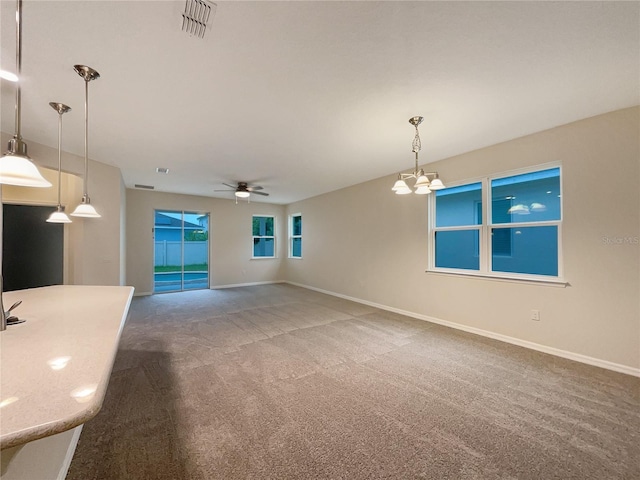 unfurnished living room featuring carpet and ceiling fan with notable chandelier