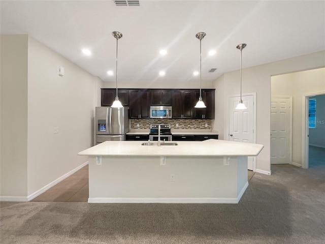 kitchen featuring sink, an island with sink, decorative light fixtures, decorative backsplash, and appliances with stainless steel finishes