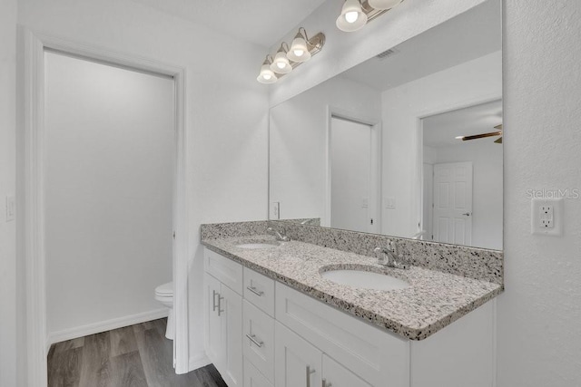 bathroom featuring dual vanity, ceiling fan, hardwood / wood-style flooring, and toilet