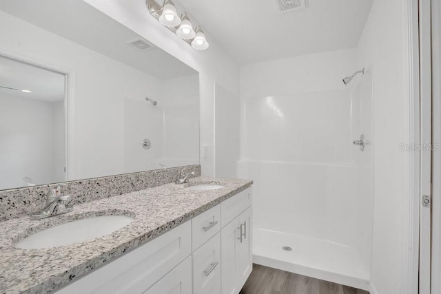 bathroom featuring walk in shower, hardwood / wood-style flooring, and dual vanity