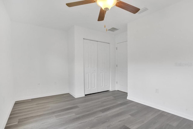 unfurnished bedroom with wood-type flooring, a closet, and ceiling fan