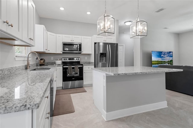 kitchen featuring sink, a kitchen island, decorative light fixtures, white cabinets, and appliances with stainless steel finishes