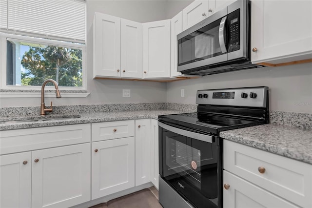 kitchen featuring white cabinetry, sink, light stone counters, and appliances with stainless steel finishes