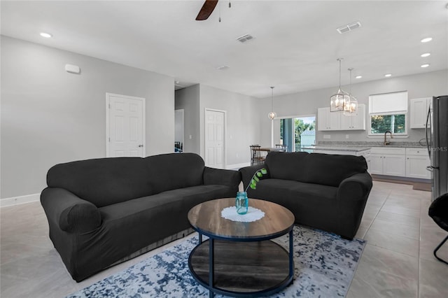 living room with ceiling fan with notable chandelier and sink