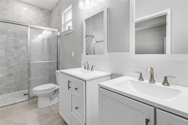 bathroom with tasteful backsplash, toilet, vanity, a shower with shower door, and tile walls