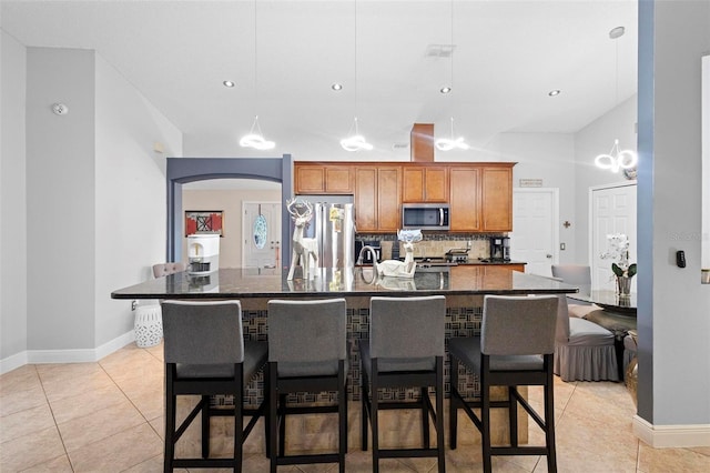 kitchen with a large island with sink, appliances with stainless steel finishes, and light tile patterned flooring