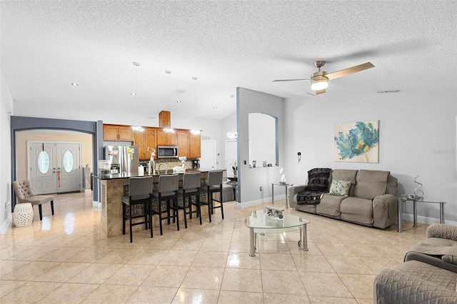 living room with ceiling fan, light tile patterned flooring, and a textured ceiling