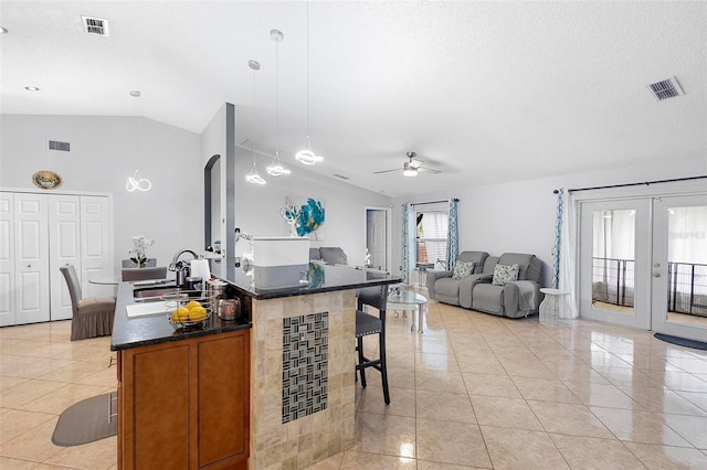 kitchen featuring ceiling fan, lofted ceiling, sink, hanging light fixtures, and an island with sink