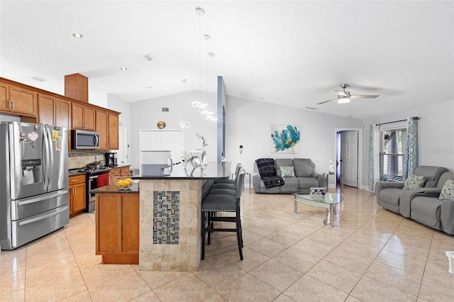 kitchen with ceiling fan, vaulted ceiling, decorative backsplash, stainless steel appliances, and light tile patterned floors