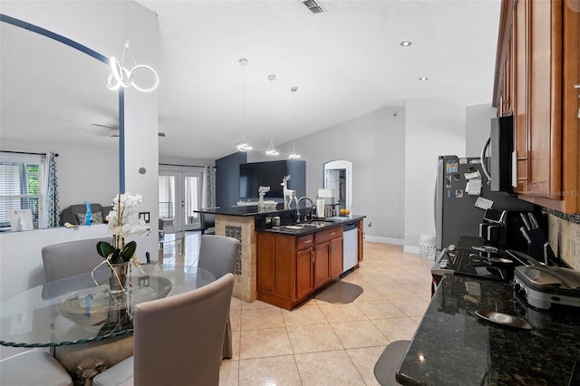 kitchen featuring pendant lighting, stainless steel appliances, dark stone counters, a kitchen island with sink, and light tile patterned flooring