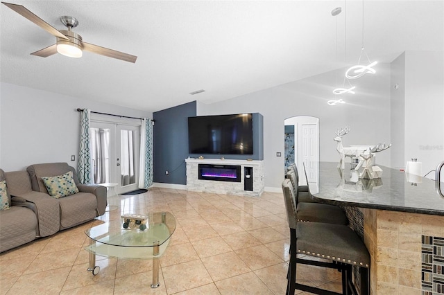 tiled living room featuring ceiling fan and vaulted ceiling