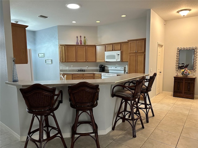 kitchen with kitchen peninsula, light tile patterned floors, and white appliances