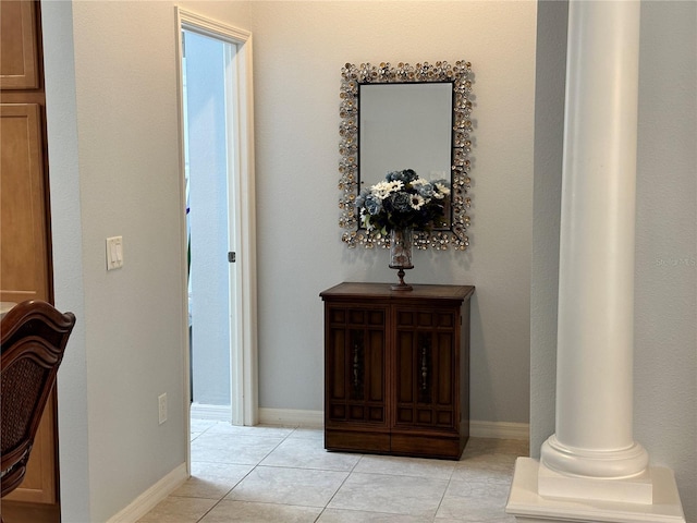 hall featuring decorative columns and light tile patterned floors