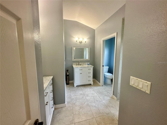 bathroom featuring tile patterned flooring, vanity, lofted ceiling, and toilet