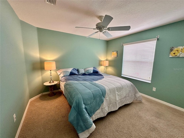 carpeted bedroom featuring ceiling fan and a textured ceiling