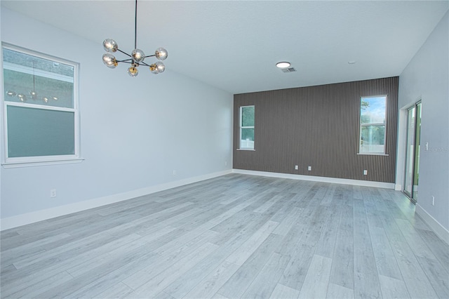 empty room featuring light wood-type flooring and a chandelier