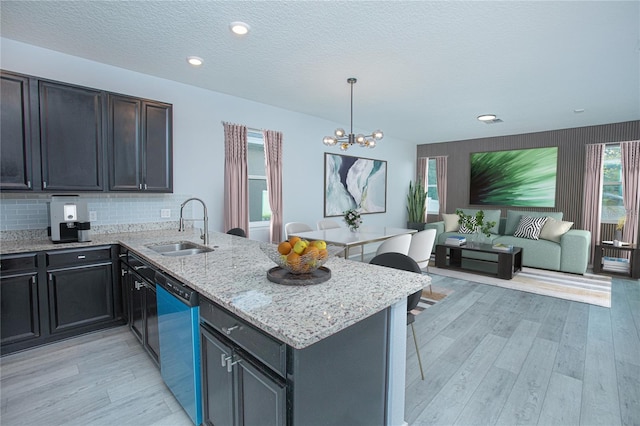 kitchen featuring sink, decorative light fixtures, dishwasher, light hardwood / wood-style floors, and tasteful backsplash