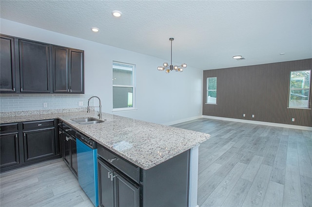 kitchen featuring dishwasher, light hardwood / wood-style flooring, pendant lighting, decorative backsplash, and sink