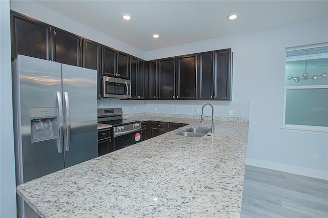 kitchen featuring light stone counters, appliances with stainless steel finishes, tasteful backsplash, and sink