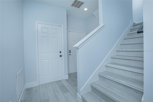 staircase featuring a textured ceiling and wood-type flooring