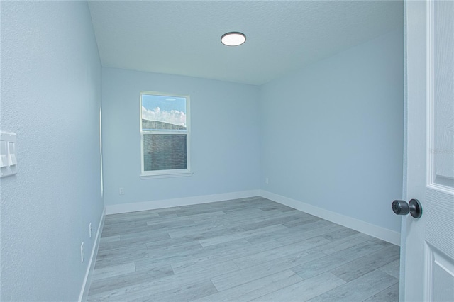 unfurnished room featuring a textured ceiling and light wood-type flooring