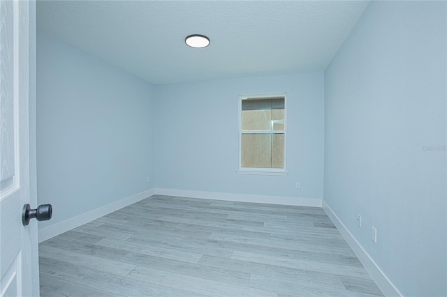 unfurnished room with a textured ceiling and light hardwood / wood-style floors