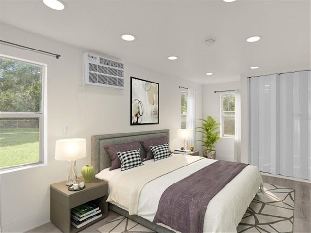 bedroom with an AC wall unit, light wood-type flooring, and multiple windows