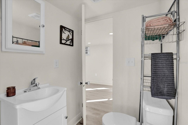 bathroom with wood-type flooring, vanity, and toilet