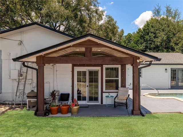 back of house with a patio area, an outdoor pool, a lawn, and french doors