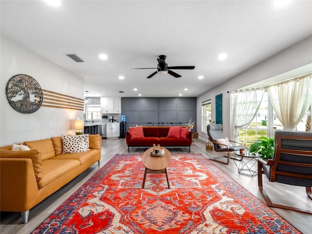 living area with visible vents, ceiling fan, a textured ceiling, light wood-style floors, and recessed lighting