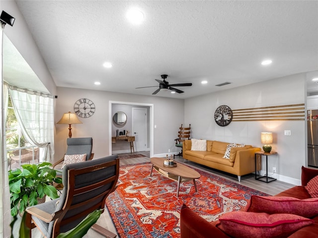 living room featuring recessed lighting, visible vents, a textured ceiling, and wood finished floors