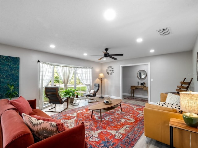 living room featuring baseboards, visible vents, a ceiling fan, light wood-type flooring, and recessed lighting