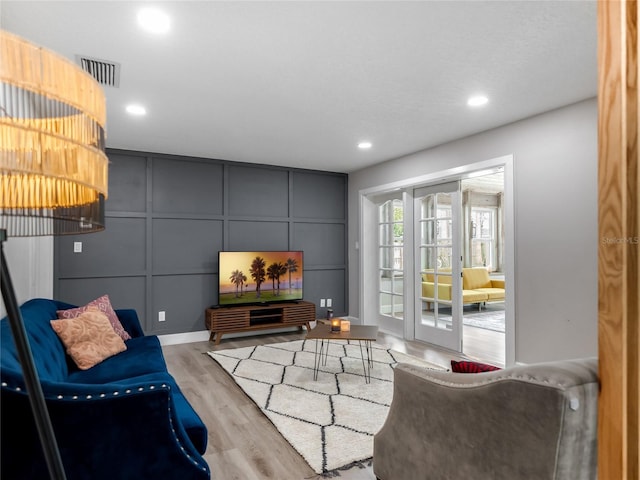 living room featuring french doors, recessed lighting, visible vents, a decorative wall, and wood finished floors