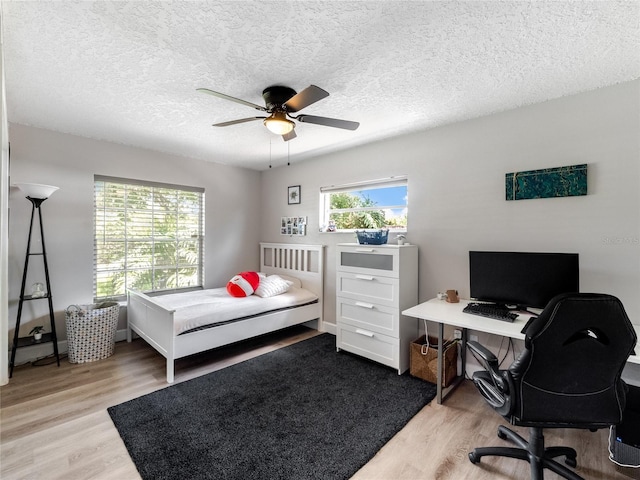 bedroom with ceiling fan, a textured ceiling, and wood finished floors