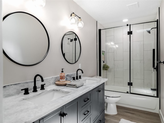 full bathroom with double vanity, wood finished floors, a sink, and toilet