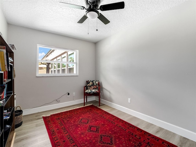 sitting room featuring a textured ceiling, wood finished floors, a ceiling fan, and baseboards