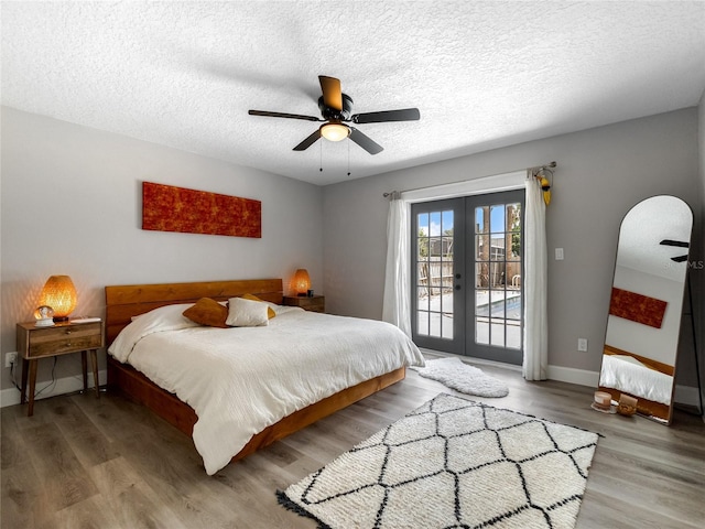 bedroom with baseboards, wood finished floors, access to exterior, a textured ceiling, and french doors